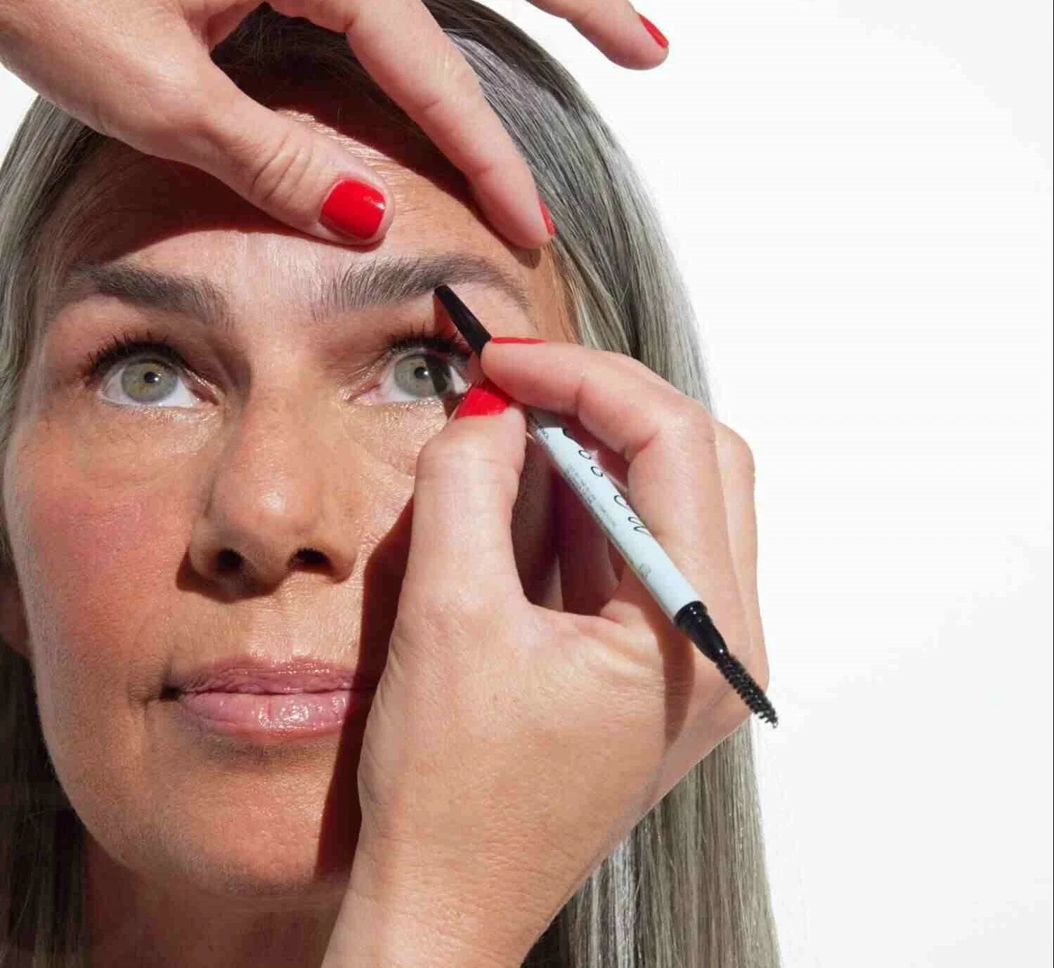 A woman showcases a Relume Cosmetics product while demonstrating how to fill in thin eyebrows for beginners naturally.