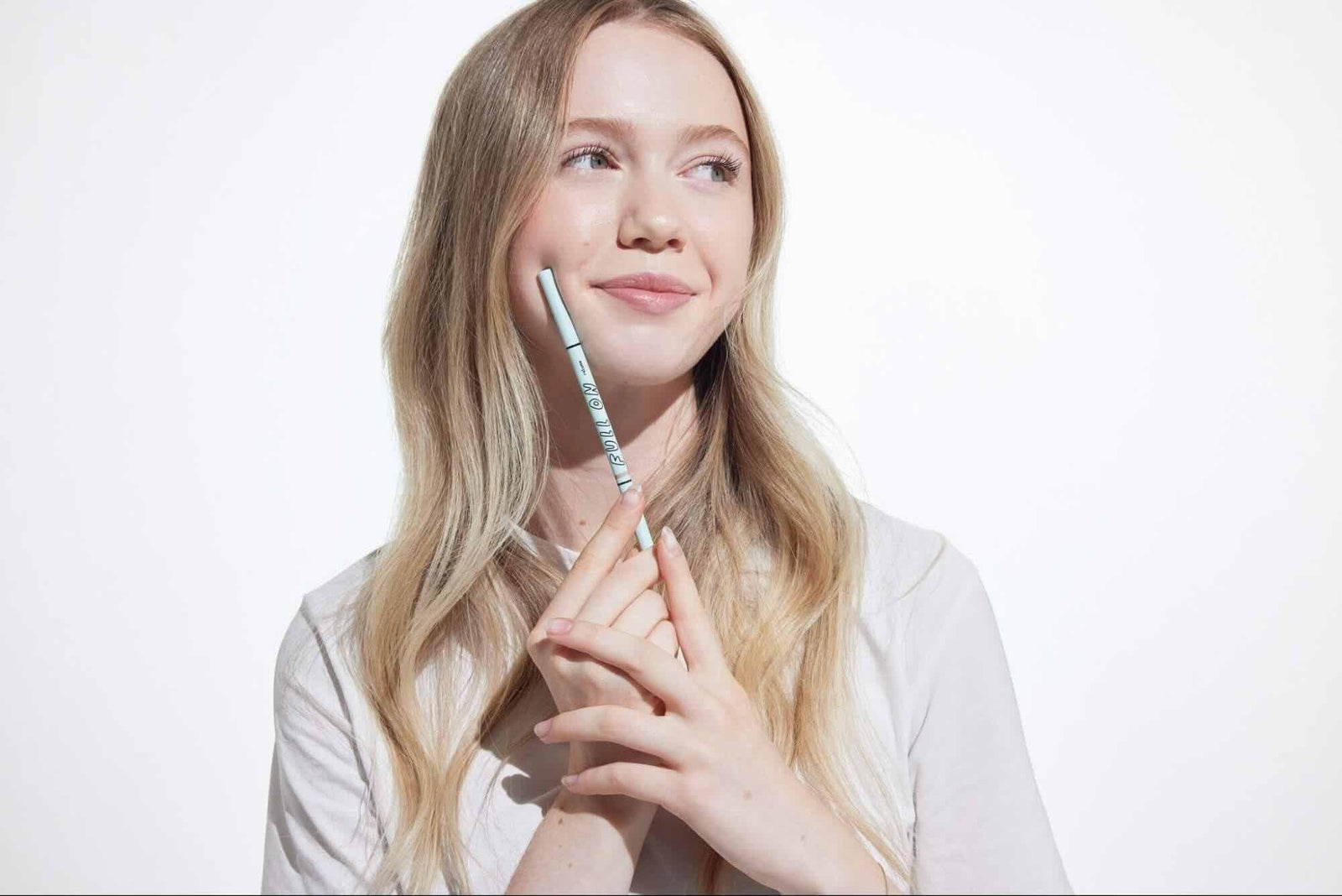 A girl placing an eyebrow product from Relume Cosmetics on her cheeks to match her hair color.